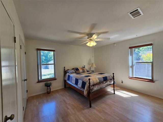 bedroom with light wood-style floors, visible vents, baseboards, and multiple windows