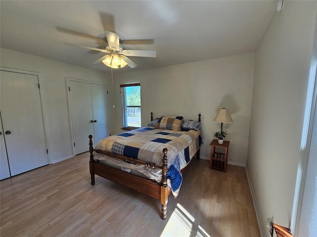 bedroom with light wood-type flooring, ceiling fan, baseboards, and two closets