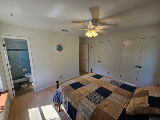 bedroom with baseboards, visible vents, ensuite bath, light wood-style floors, and multiple closets