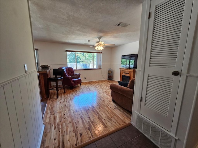 living area featuring wainscoting, a fireplace, wood finished floors, and visible vents