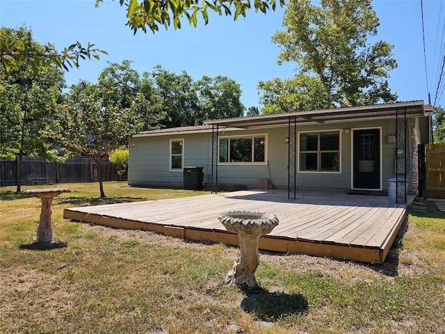 back of property with a deck, a yard, cooling unit, and fence