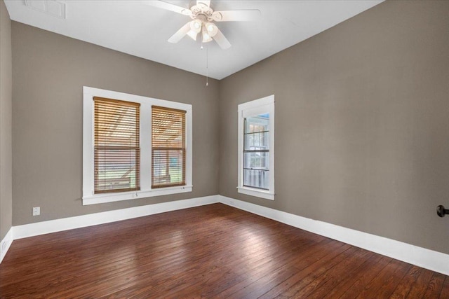 empty room with dark wood-type flooring, visible vents, ceiling fan, and baseboards