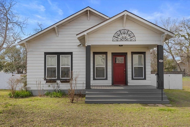 bungalow featuring a porch, a front yard, and fence