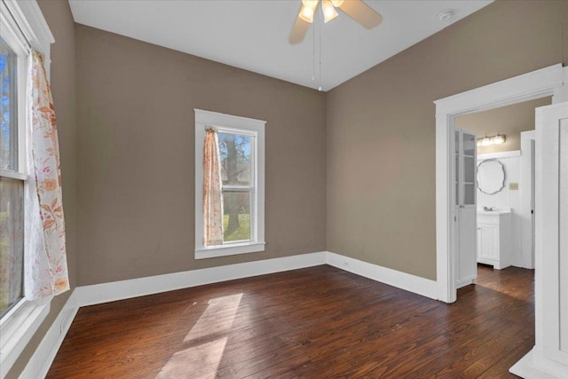 empty room with lofted ceiling, dark wood finished floors, a ceiling fan, and baseboards