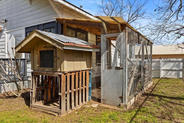 exterior space featuring metal roof, fence, and an outdoor structure