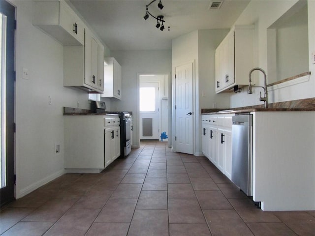 kitchen featuring dark countertops, stainless steel dishwasher, gas stove, and white cabinets