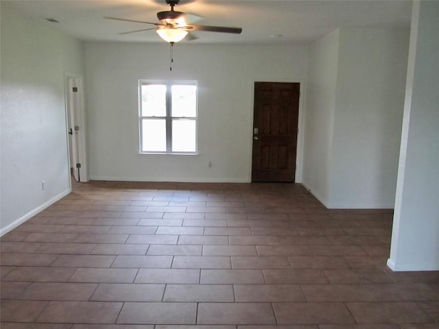 tiled spare room featuring visible vents, ceiling fan, and baseboards