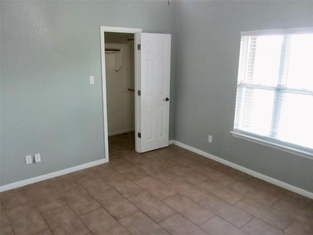 unfurnished bedroom featuring a spacious closet, a closet, and baseboards