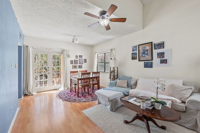 living room with plenty of natural light, french doors, light wood finished floors, and a textured ceiling