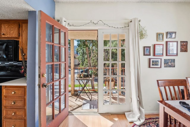 doorway with wood finished floors and a textured ceiling