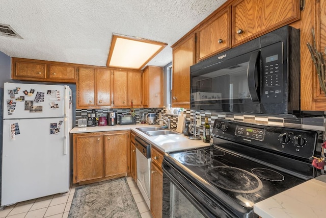 kitchen with brown cabinetry, visible vents, black appliances, and a sink