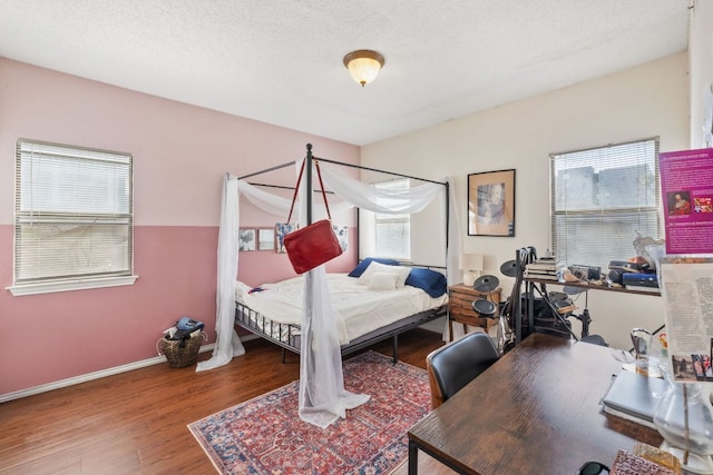 bedroom with a textured ceiling, baseboards, and wood finished floors