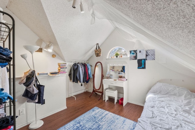 bedroom with vaulted ceiling, a textured ceiling, baseboards, and wood finished floors