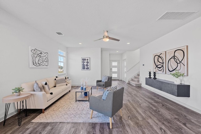 living room featuring stairs, visible vents, and wood finished floors