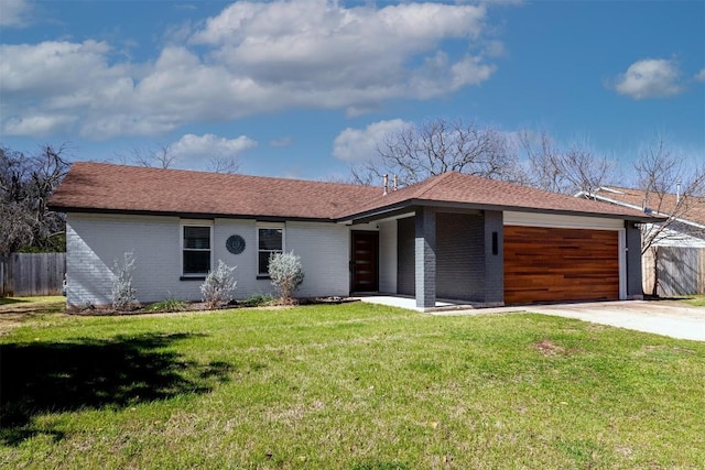 view of front of property featuring a garage, driveway, fence, a front lawn, and brick siding