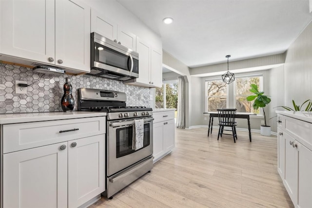 kitchen featuring decorative backsplash, appliances with stainless steel finishes, light countertops, light wood-style floors, and a wealth of natural light