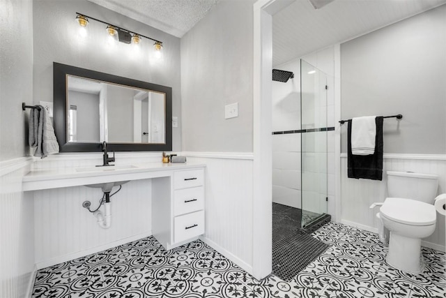 bathroom featuring toilet, a wainscoted wall, and a shower stall