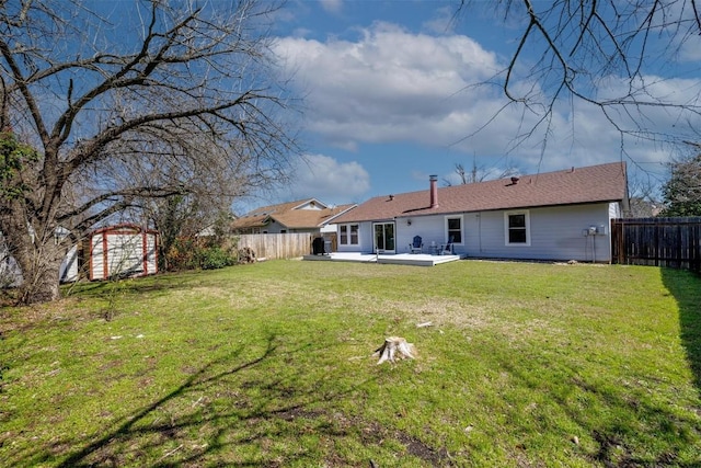 rear view of house featuring an outbuilding, a yard, and a fenced backyard