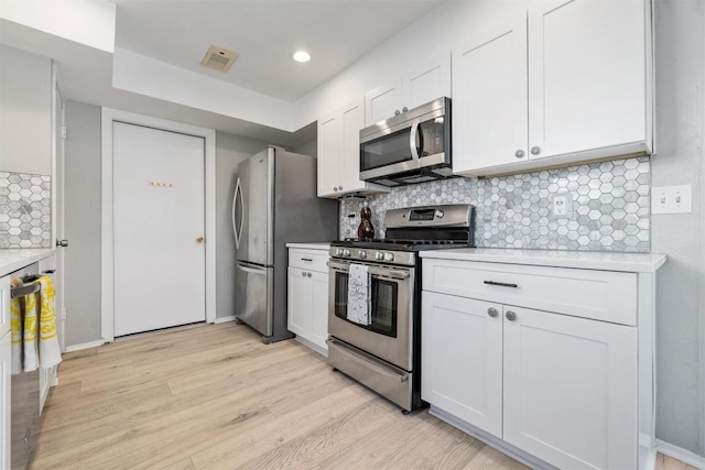 kitchen with tasteful backsplash, visible vents, stainless steel appliances, light countertops, and light wood-type flooring