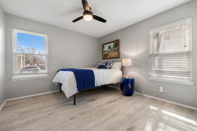 bedroom with a textured ceiling, baseboards, and wood finished floors