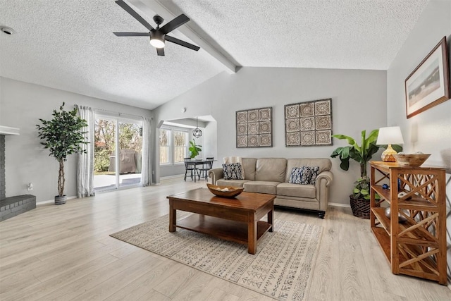 living room with vaulted ceiling with beams, a fireplace, a ceiling fan, a textured ceiling, and light wood-type flooring