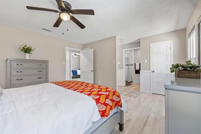 bedroom with light wood-style flooring, visible vents, ceiling fan, and a textured ceiling