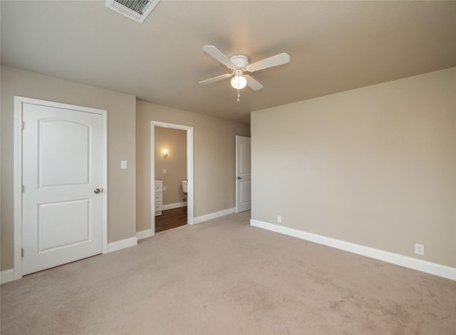 unfurnished bedroom with light colored carpet, visible vents, ensuite bathroom, a ceiling fan, and baseboards