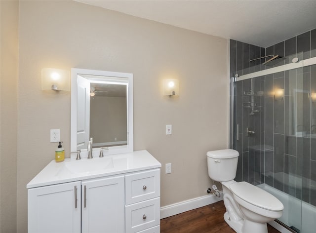 full bathroom with baseboards, toilet, wood finished floors, a tile shower, and vanity