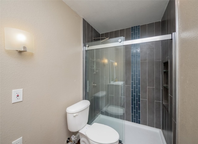 bathroom with a textured wall, a shower stall, and toilet