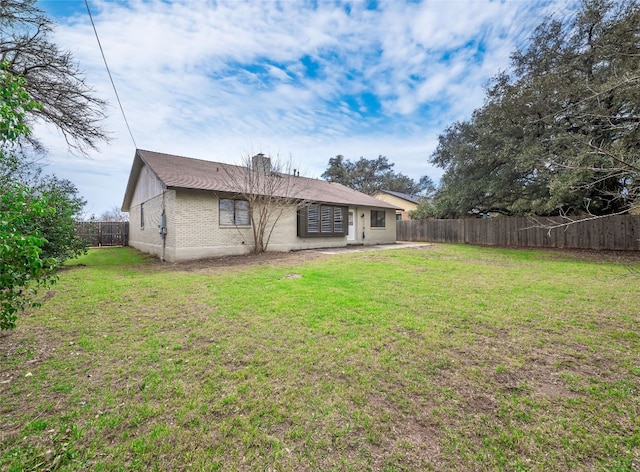 back of property featuring brick siding, a lawn, a chimney, and a fenced backyard