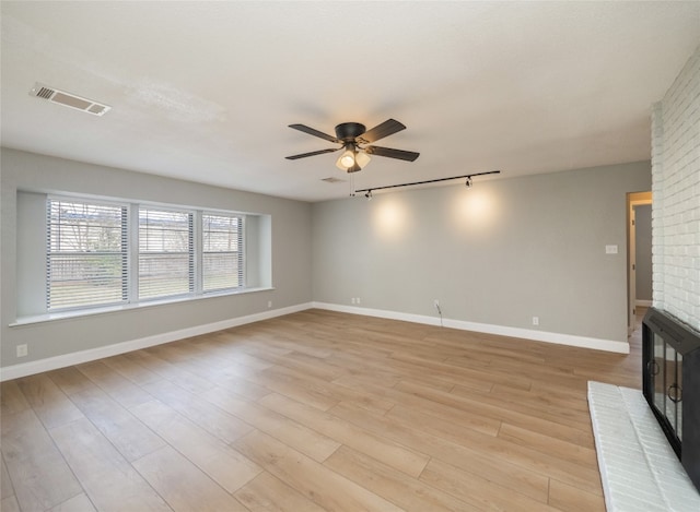 unfurnished living room with baseboards, visible vents, a ceiling fan, light wood-style flooring, and rail lighting