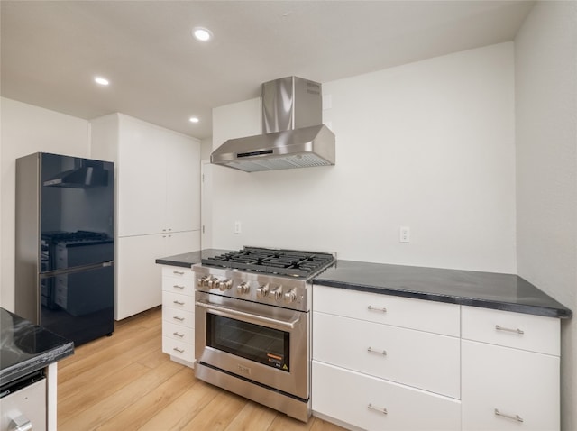 kitchen featuring dark countertops, light wood-style floors, wall chimney exhaust hood, and high end range