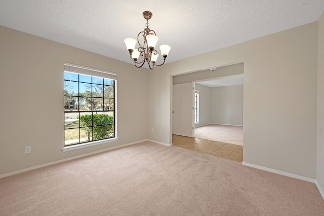 empty room with baseboards, light colored carpet, a chandelier, and a textured ceiling