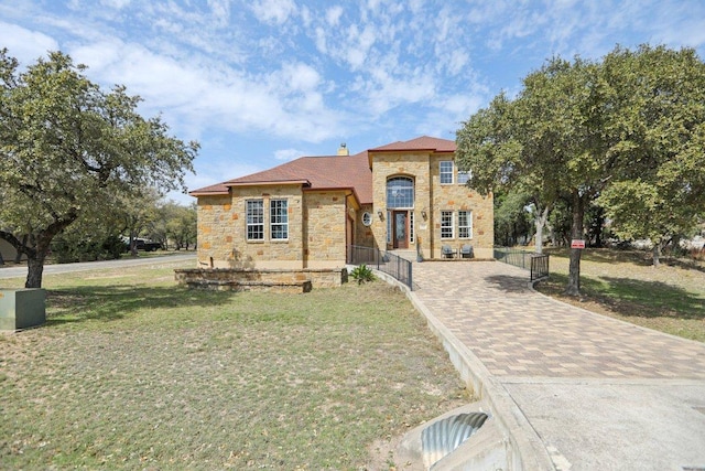 view of front facade with fence private yard, a front yard, driveway, and stone siding