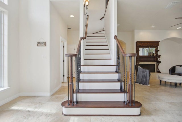 stairway featuring visible vents, recessed lighting, baseboards, and arched walkways