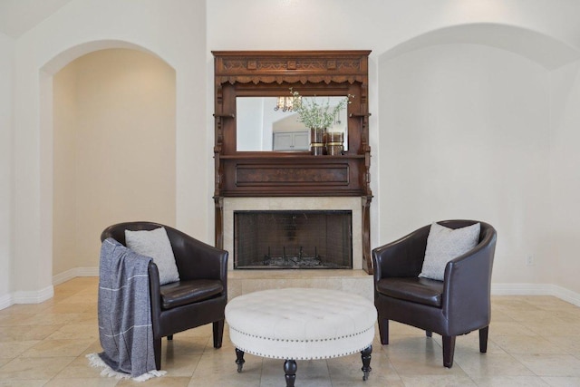 sitting room with baseboards, light tile patterned floors, arched walkways, and a premium fireplace