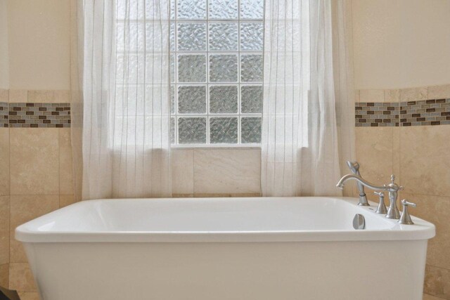 full bathroom featuring tile walls and a freestanding tub