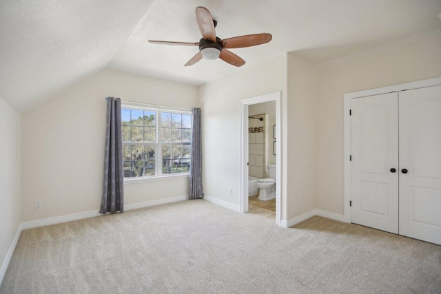 unfurnished bedroom featuring baseboards, a closet, lofted ceiling, and carpet