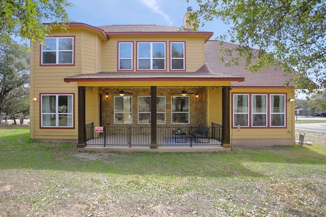 rear view of house with a chimney, a patio area, roof with shingles, ceiling fan, and a yard
