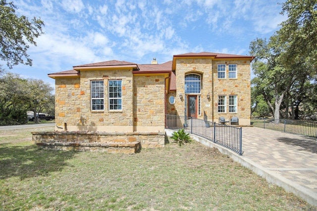 view of front of house with fence, a chimney, a front lawn, and stone siding