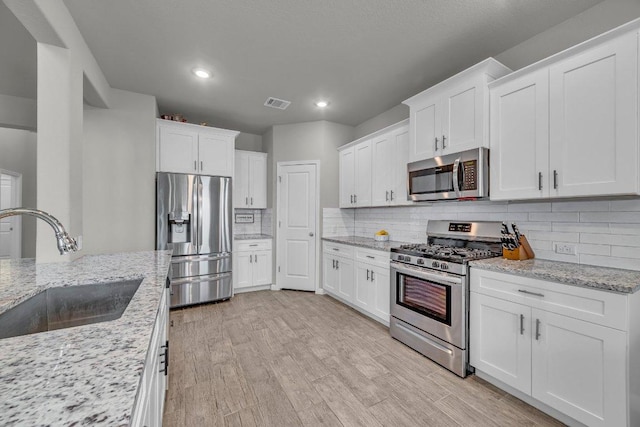 kitchen featuring visible vents, appliances with stainless steel finishes, light wood-style flooring, and a sink