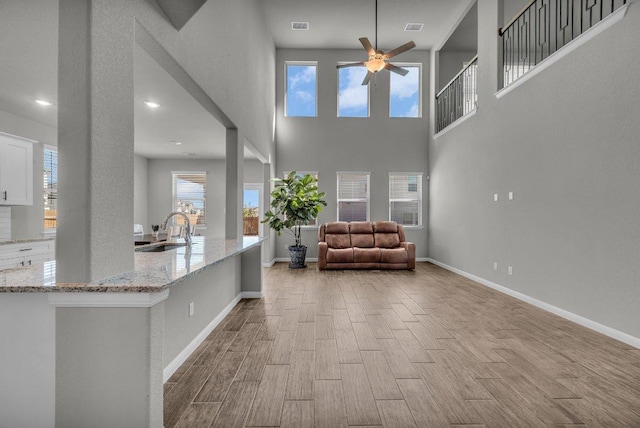 unfurnished room featuring wood finished floors, a sink, visible vents, and baseboards