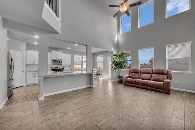 interior space with stainless steel appliances, a sink, white cabinetry, open floor plan, and wood tiled floor