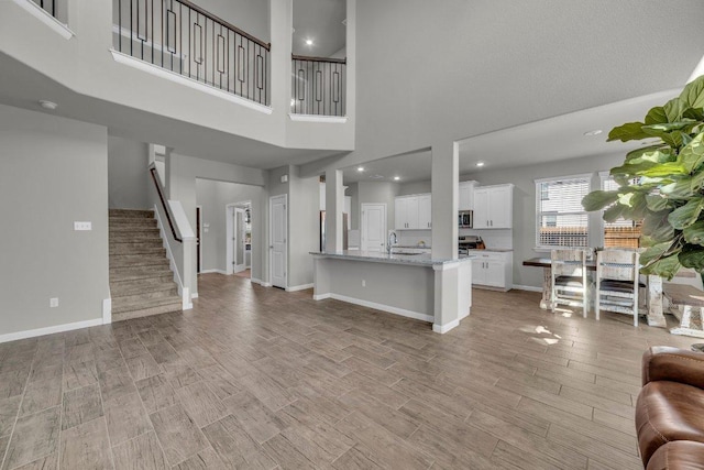 living area with stairs, recessed lighting, light wood-type flooring, and baseboards