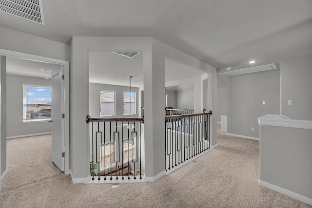 corridor featuring carpet floors, baseboards, and visible vents