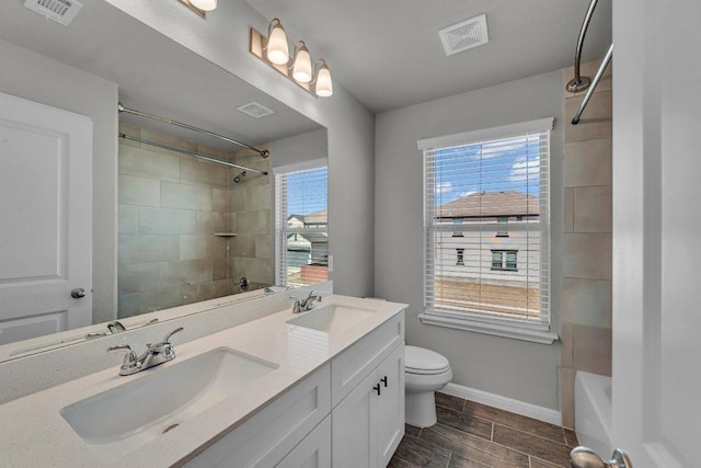 full bath featuring toilet, a sink, and visible vents