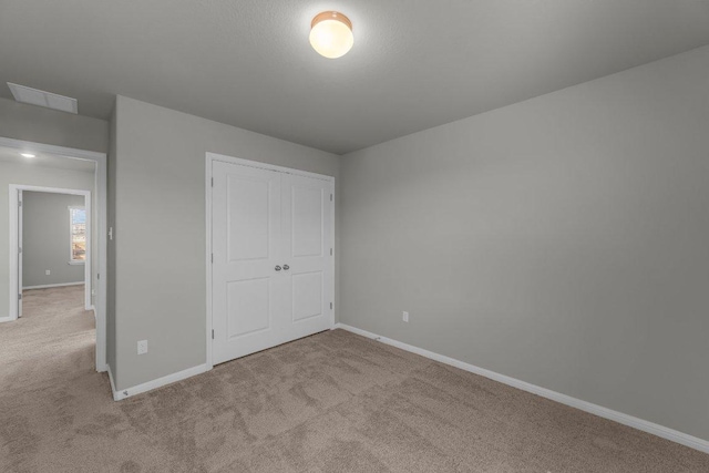 unfurnished bedroom featuring carpet, a closet, visible vents, and baseboards