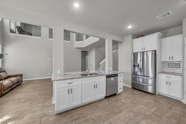 kitchen with stainless steel appliances, a sink, visible vents, open floor plan, and light wood finished floors