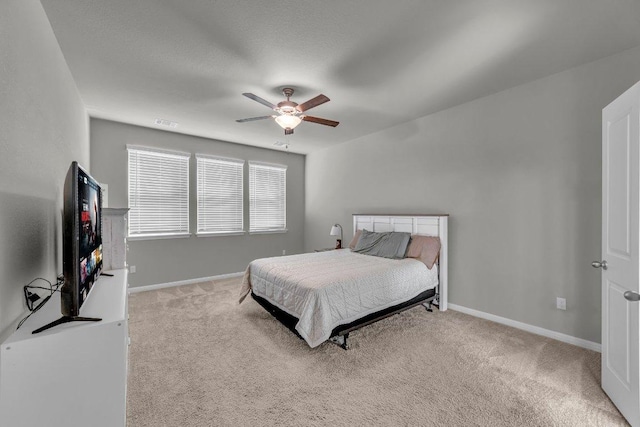 bedroom featuring light carpet, visible vents, a ceiling fan, and baseboards