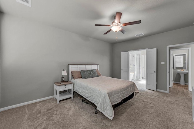 carpeted bedroom featuring baseboards, visible vents, a sink, and ensuite bathroom